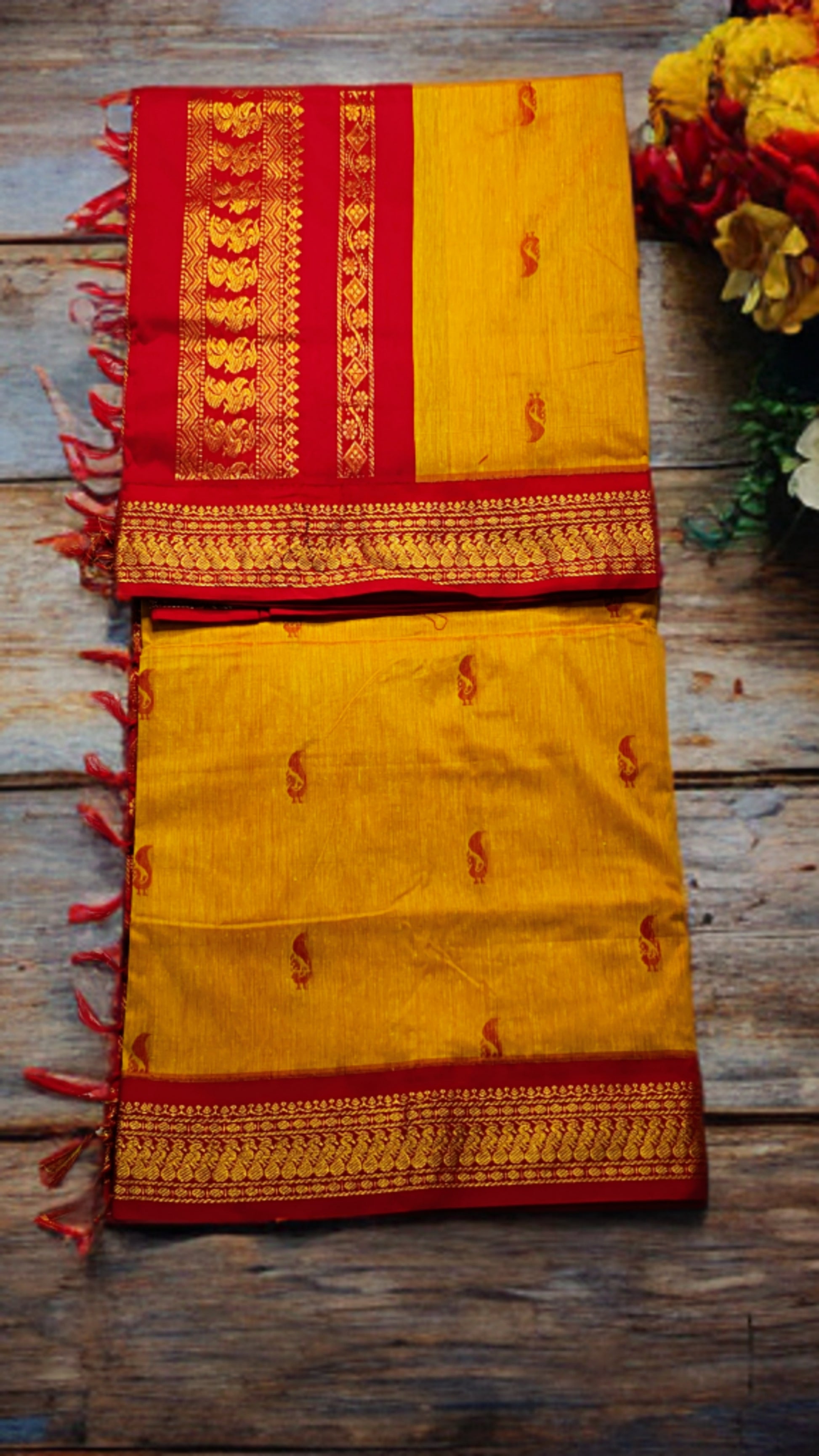 Yellow saree with red border on a wooden surface